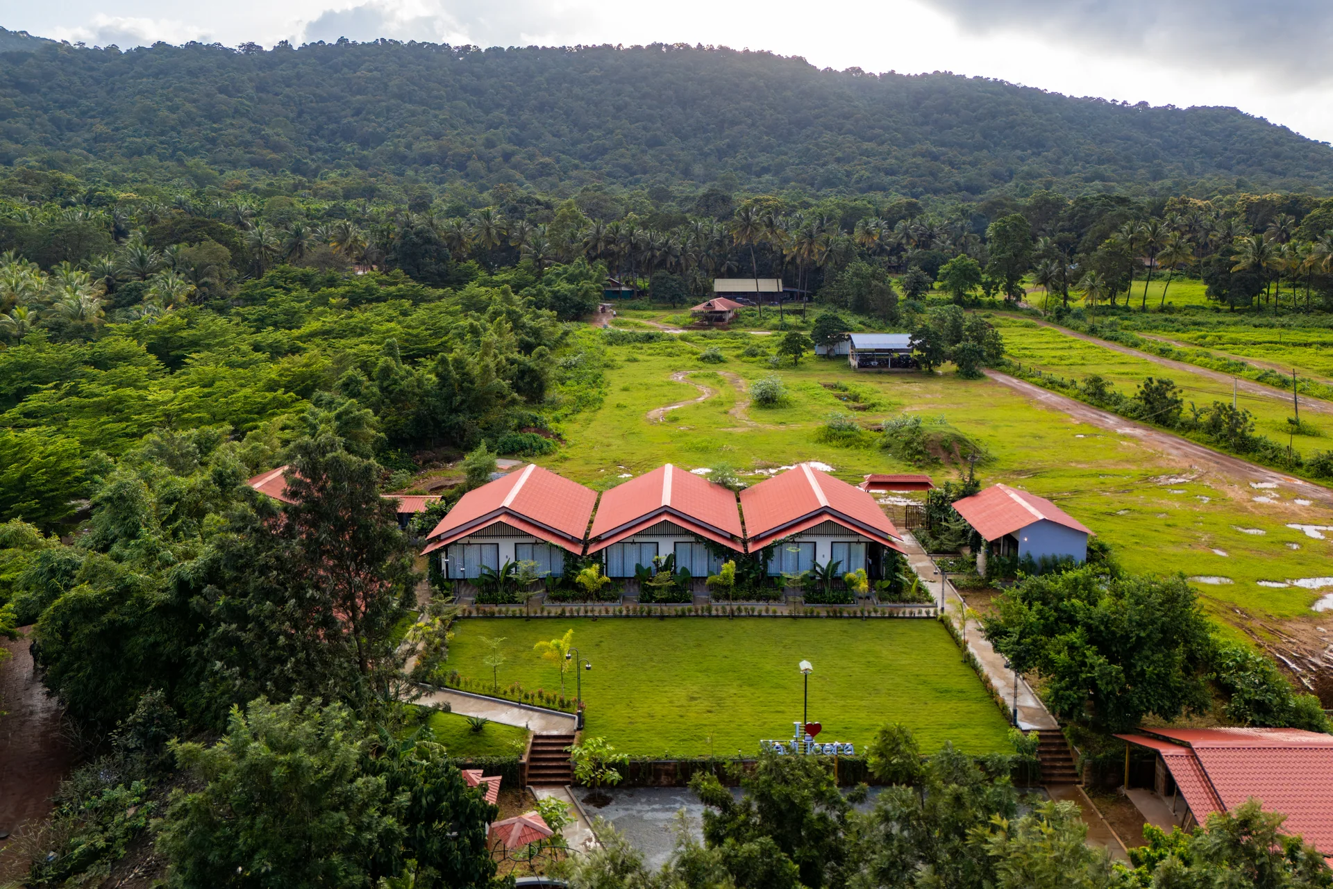 Cottages surrounded by green hills at Nadi Teera, Dandeli