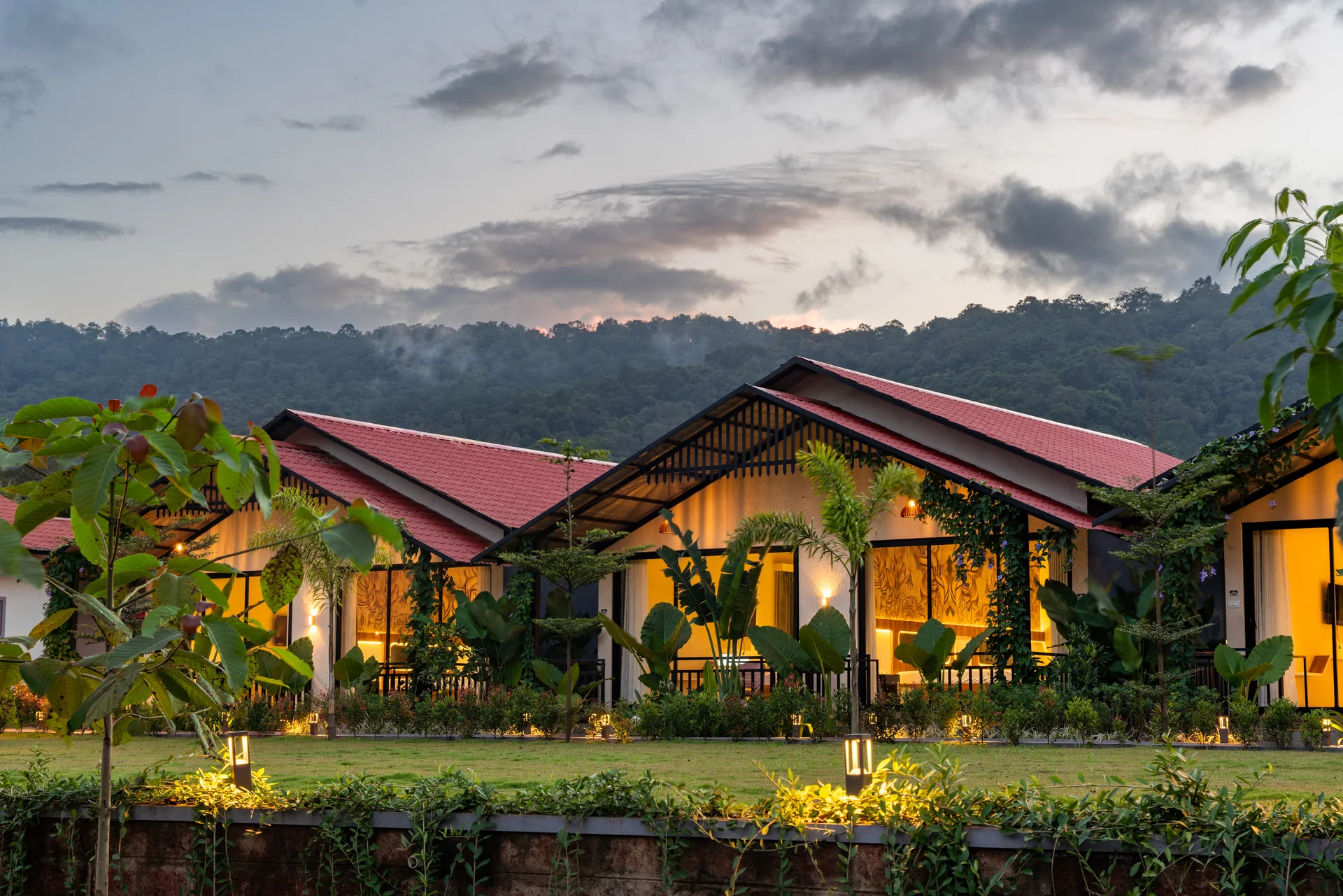 Premium Cottage exterior at dusk at Nadi Teera, Dandeli